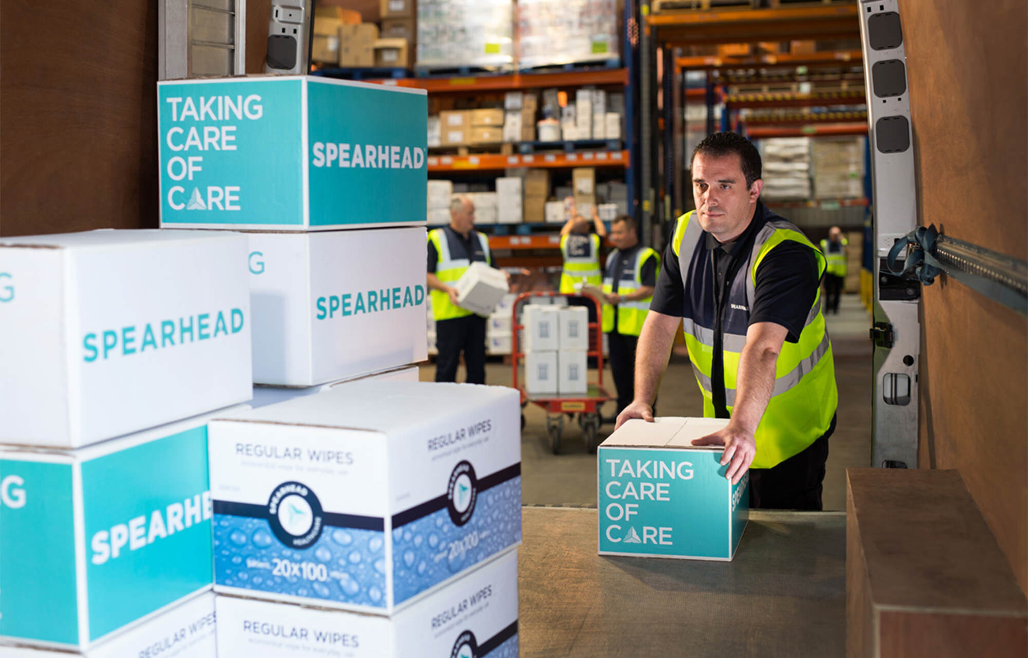 Man packing Spearhead Healthcare boxes into a van