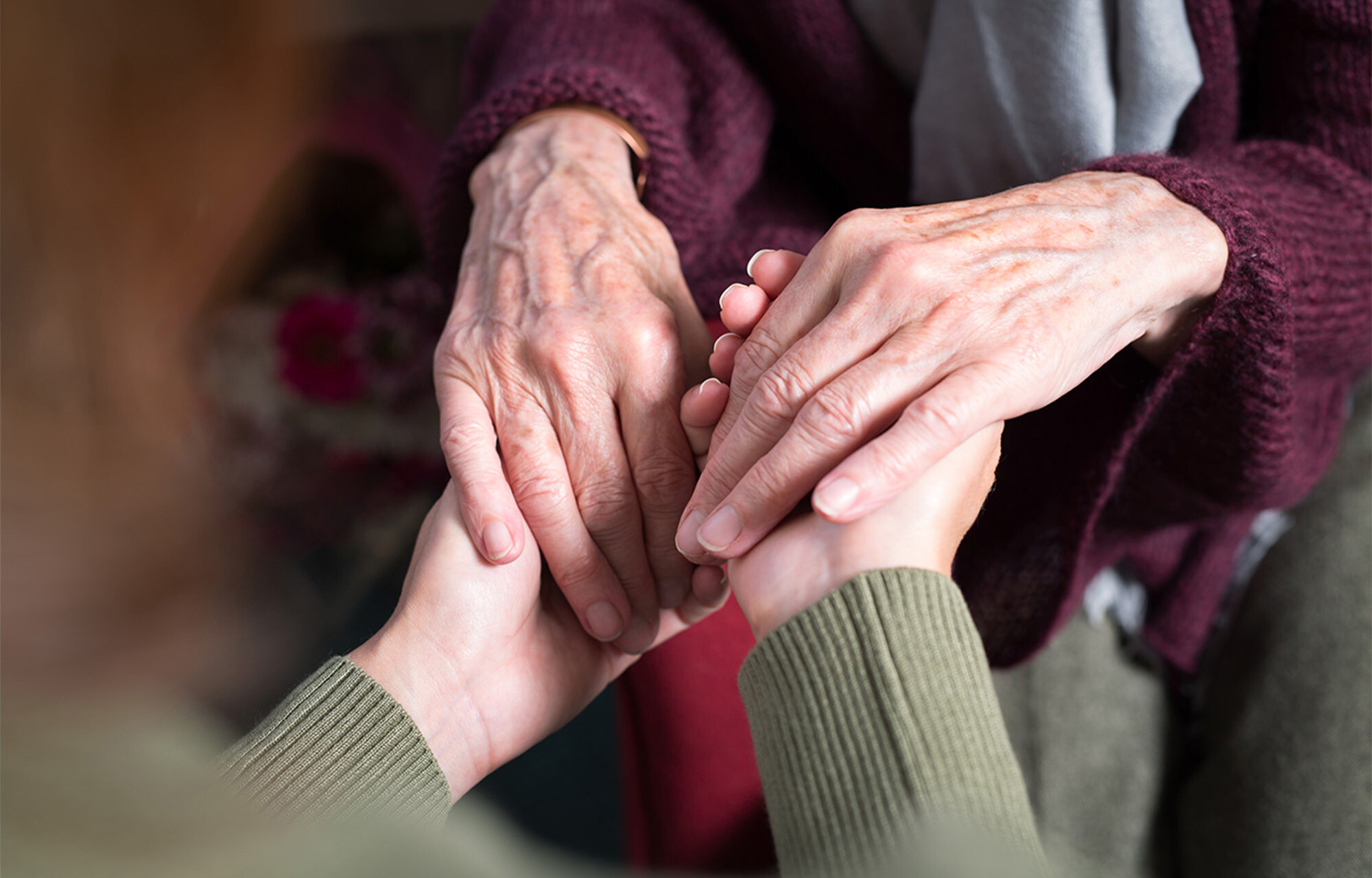 Elderly woman holding hands with a healthcare worker